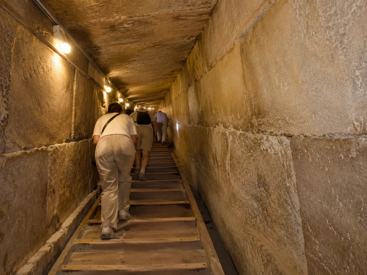 Visitors climbing the wooden ramp up the Grand Gallery inside the Great Pyramid